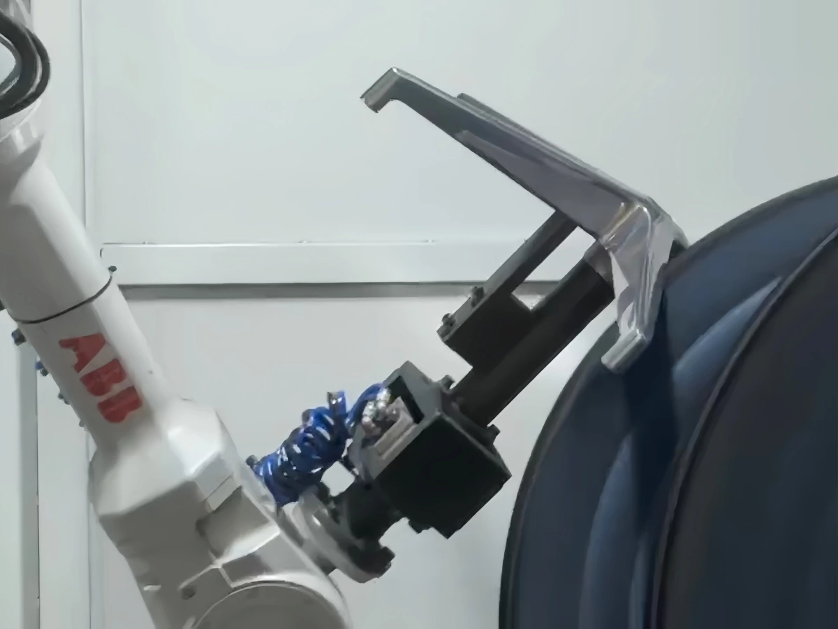 Robot gripper holding a metal workpiece against a polishing wheel during process testing